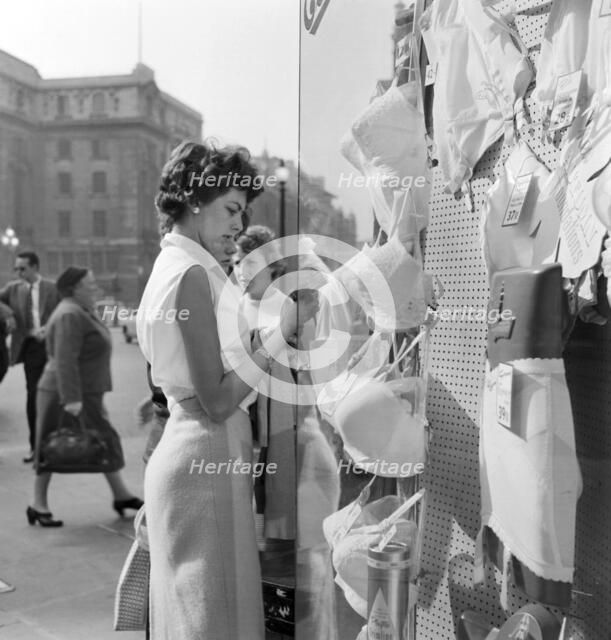 A young woman looking in the window of a lingerie shop in Piccadilly Circus, London, c1946-c1959. Artist: John Gay