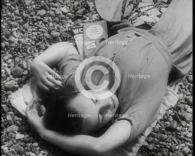A Young Woman Lying on the Beach at  Brighton With Her Eyes Closed With a Two Books to the..., 1939. Creator: British Pathe Ltd.