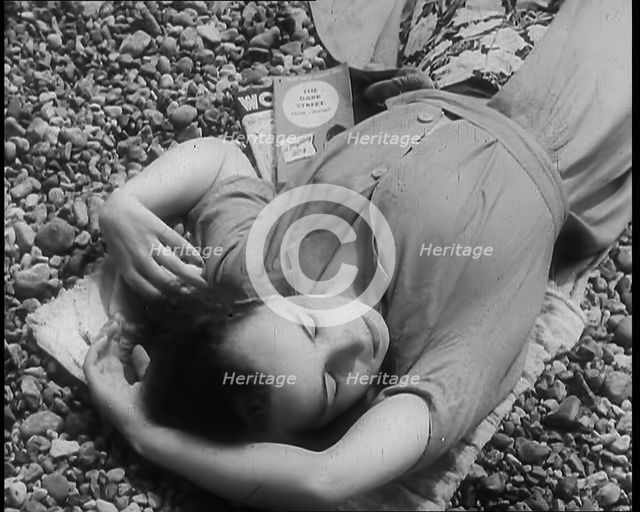 A Young Woman Lying on the Beach at  Brighton With Her Eyes Closed With a Two Books to the..., 1939. Creator: British Pathe Ltd.