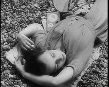A Young Woman Lying on the Beach at Brighton With Her Eyes Closed With a Two Books to the..., 1939. Creator: British Pathe Ltd