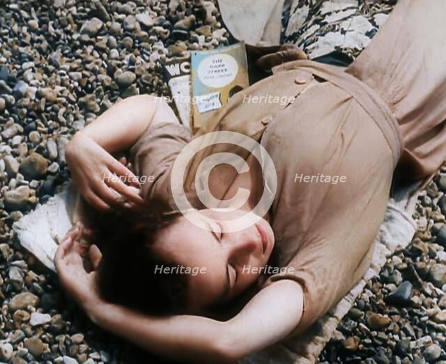 A Young Woman Lying on the Beach at  Brighton With Her Eyes Closed With a Two Books to the..., 1939. Creator: British Pathe Ltd.