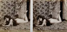 A young woman posing naked in a photographic studio, lying on her front on a piece of..., c1900. Creator: Unknown