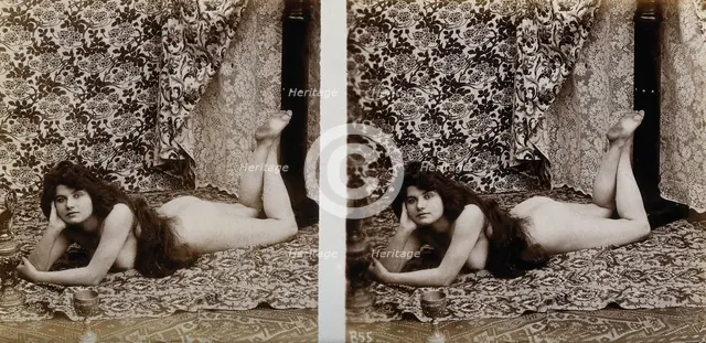 A young woman posing naked in a photographic studio, lying on her front on a piece of..., c1900. Creator: Unknown.