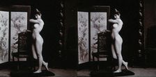 A young woman posing naked in a photographic studio, leaning on the back of a chair..., c1900. Creator: Unknown