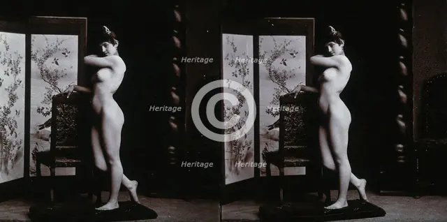 A young woman posing naked in a photographic studio, leaning on the back of a chair..., c1900. Creator: Unknown.