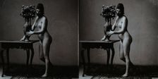 A young woman posing naked in a photographic studio, standing in front of a table on which..., c1900 Creator: Unknown