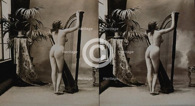 A young woman posing naked in a photographic studio, standing with her back to the camera..., c1900. Creator: Unknown.