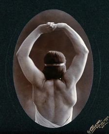A young woman posing semi-naked, back view, with her arms in the air, in a photographic..., c1903. Creator: Unknown