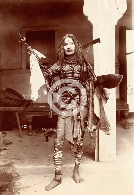 A young Indian man wearing many beads and makeup in a temple precinct, c1900. Creator: Unknown.