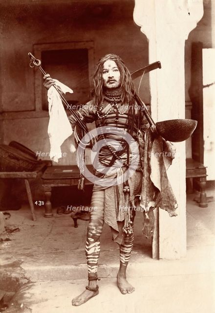A young Indian man wearing many beads and makeup in a temple precinct, c1900. Creator: Unknown.