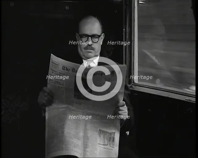 A Bald Man Wearing Spectacles Reading 'The Daily Telegraph' in the Carriage of a Train..., 1938. Creator: British Pathe Ltd.