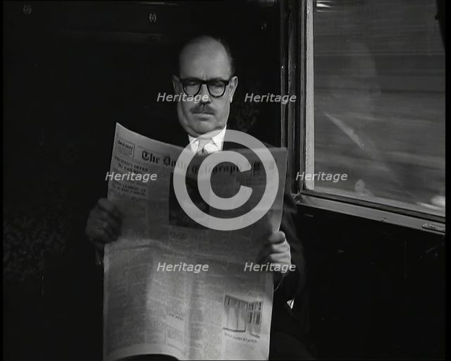 A Bald Man Wearing Spectacles Reading 'The Daily Telegraph' in the Carriage of a Train..., 1938. Creator: British Pathe Ltd.