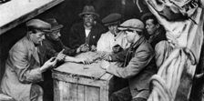 A bargee and his mates play dominoes in the hold of a canal boat, 1926-1927