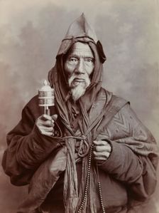 A bearded elderly man, carrying a prayer wheel and a rosary, in a studio setting, c1900. Creator: Thomas Parr