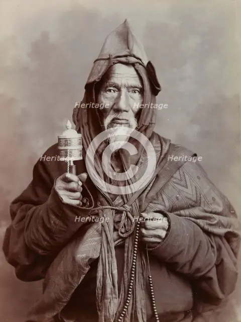 A bearded elderly man, carrying a prayer wheel and a rosary, in a studio setting, c1900. Creator: Thomas Parr.
