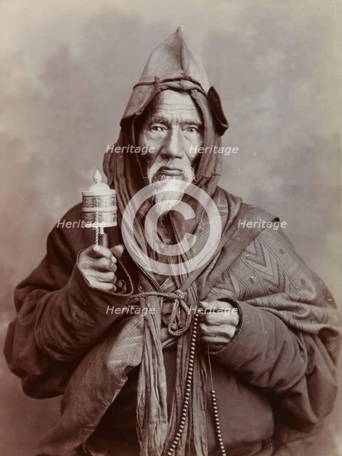 A bearded elderly man, carrying a prayer wheel and a rosary, in a studio setting, c1900. Creator: Thomas Parr.