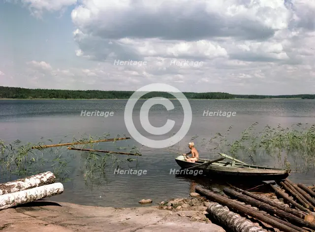 A boy fishing from a rowing boat during his summer holidays, Sweden, 1950s. Creator: Göran Algård.