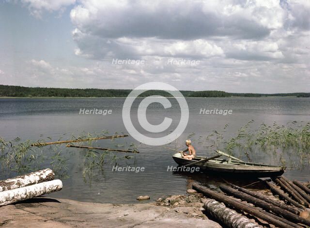 A boy fishing from a rowing boat during his summer holidays, Sweden, 1950s. Artist: Göran Algård