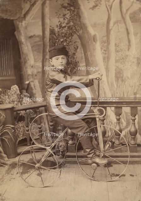 A boy on a bicycle in a photo studio, 1880. Creator: Unknown.
