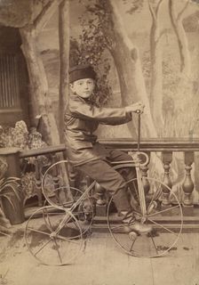 A boy on a bicycle in a photo studio, 1880. Creator: Unknown