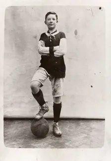 A boy poses in football kit, 1910
