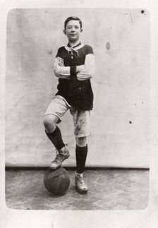 A boy poses in football kit, 1910
