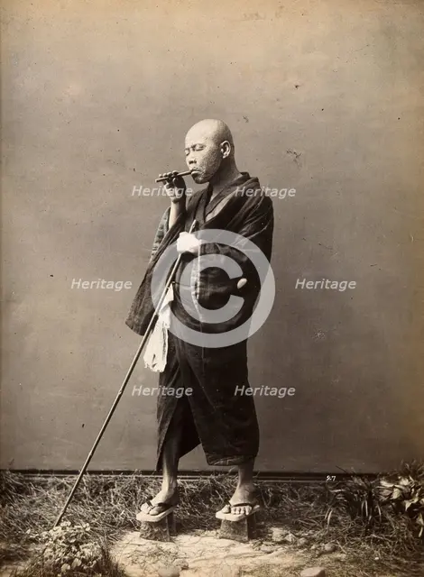 A blind Japanese masseur with a pipe in his mouth and a long pole in his hand, c1890s. Creator: Unknown.
