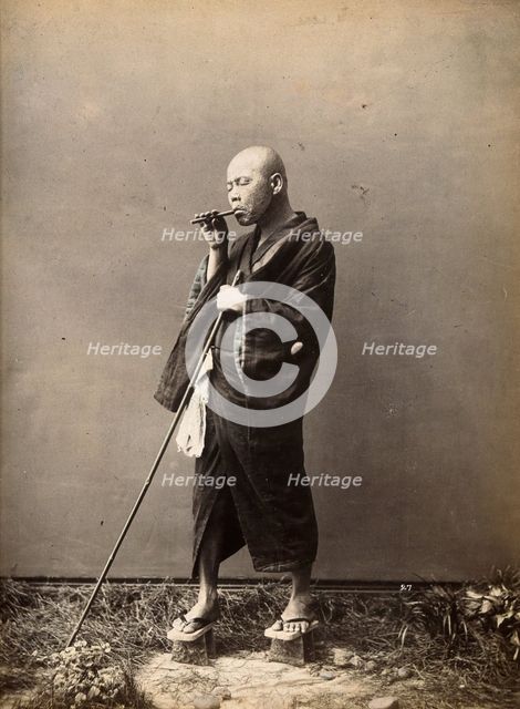 A blind Japanese masseur with a pipe in his mouth and a long pole in his hand, c1890s. Creator: Unknown.