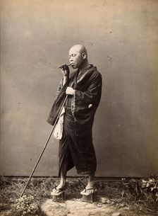 A blind Japanese masseur with a pipe in his mouth and a long pole in his hand, c1890s. Creator: Unknown