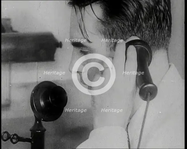 A British Man Holding a Candlestick Telephone Receiver to His Ear and Speaking Into the..., 1939. Creator: British Pathe Ltd.