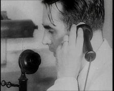 A British Man Holding a Candlestick Telephone Receiver to His Ear and Speaking Into the..., 1939. Creator: British Pathe Ltd