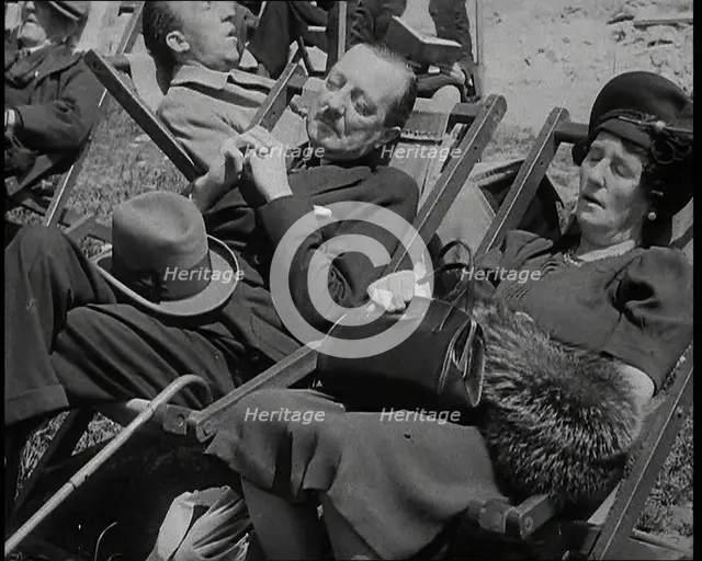 A British Couple Asleep in Deckchairs in the Sunshine in Hyde Park, the Man Has His Legs.., 1938. Creator: British Pathe Ltd.