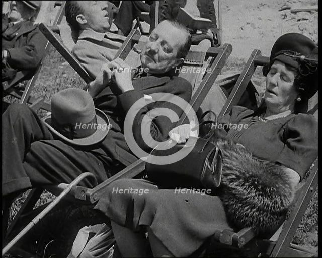 A British Couple Asleep in Deckchairs in the Sunshine in Hyde Park, the Man Has His Legs.., 1938. Creator: British Pathe Ltd.