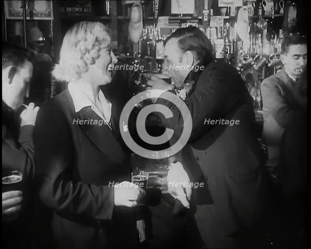 A British Woman and a British Man Standing at  the Bar Holding Drinks in a Public House..., 1939. Creator: British Pathe Ltd.