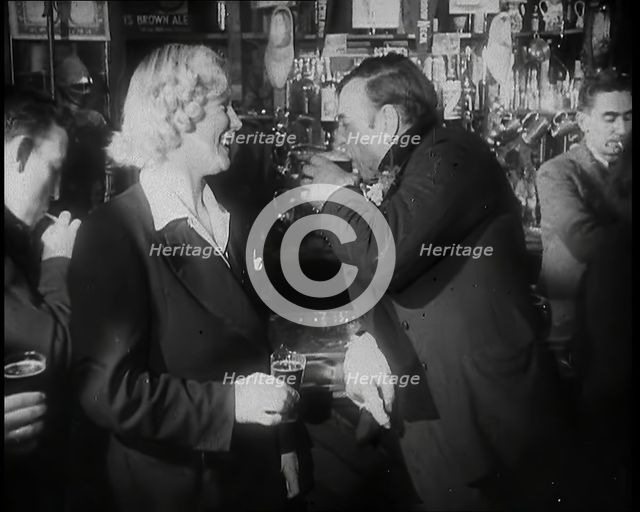 A British Woman and a British Man Standing at  the Bar Holding Drinks in a Public House..., 1939. Creator: British Pathe Ltd.