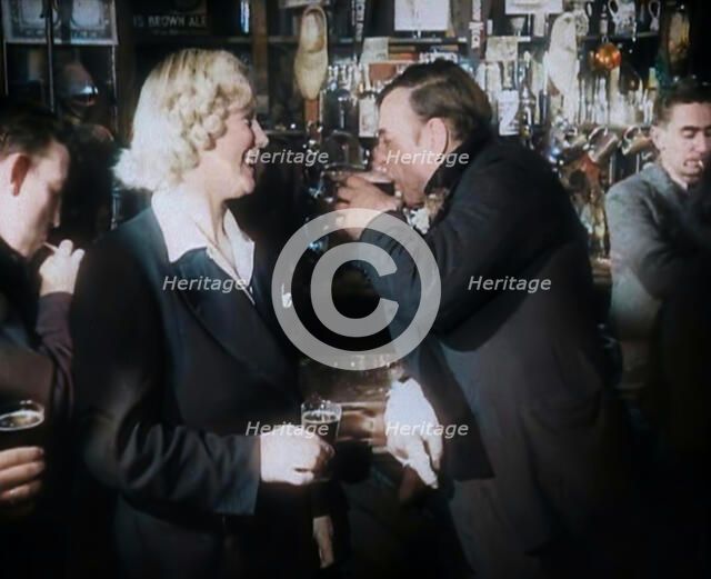 A British Woman and a British Man Standing at  the Bar Holding Drinks in a Public House..., 1939. Creator: British Pathe Ltd.