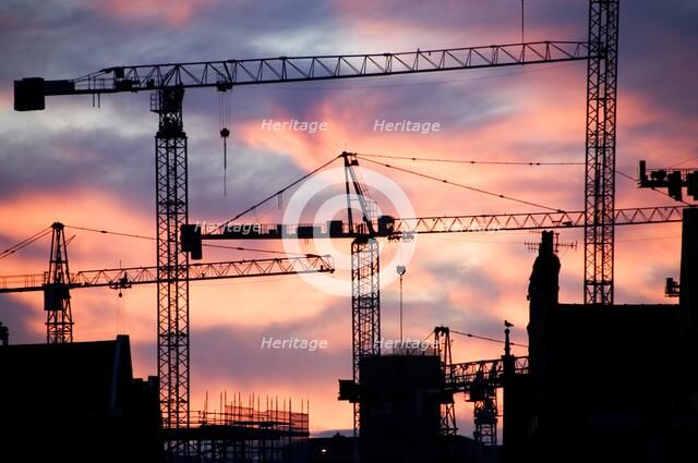 A building site at sunset with cranes silhouetted against a red sky, 2007. Artist: Historic England Staff Photographer.