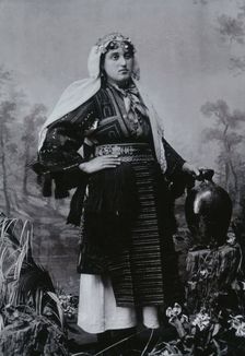 A Bulgarian woman in national dress with a water jug, early 20th century. Creator: Unknown