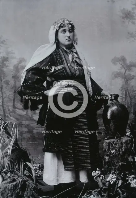 A Bulgarian woman in national dress with a water jug, early 20th century. Creator: Unknown.