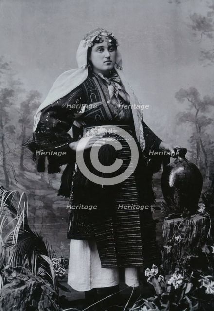 A Bulgarian woman in national dress with a water jug, early 20th century. Creator: Unknown.