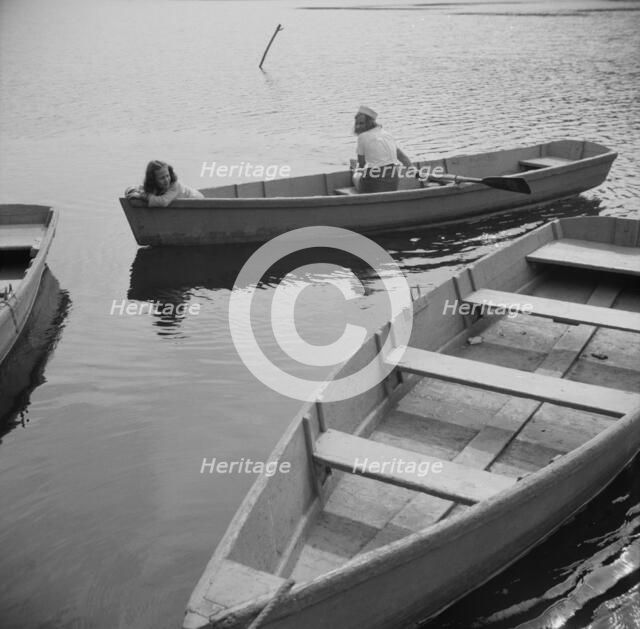A camper returning a boat to the dock at Camp Gaylord White, Arden, New York, 1943. Creator: Gordon Parks.