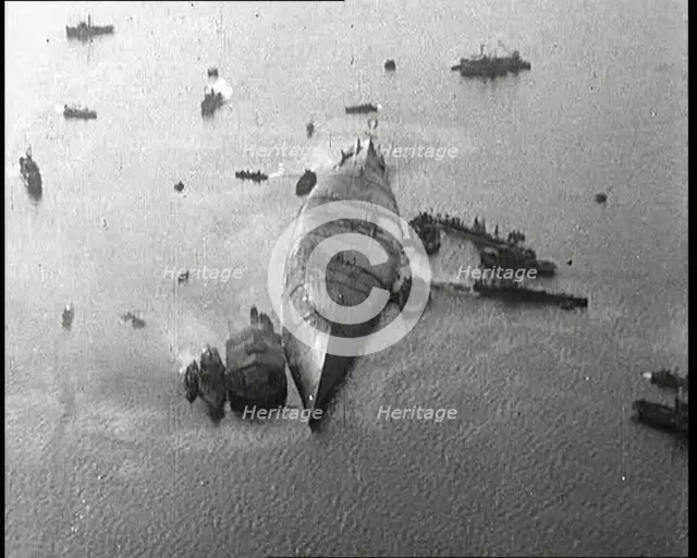 A Capsized Italian Ship at Sea Being Approached by Smaller Vessels, 1921. Creator: British Pathe Ltd.