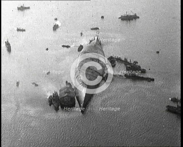 A Capsized Italian Ship at Sea Being Approached by Smaller Vessels, 1921. Creator: British Pathe Ltd.