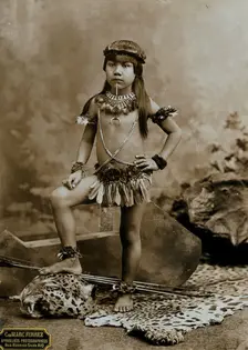 A child of an Amazonian Indian tribe, standing on a leopard skin, in a photographic studio, 1900. Creator: Unknown