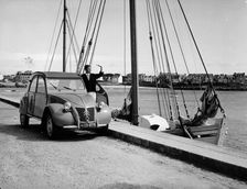 A Citroën 2CV on the quay at a harbour, c1957