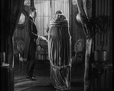 A Civilian Couple Wearing Evening Outfits Entering a Drawing Room, 1920. Creator: British Pathe Ltd