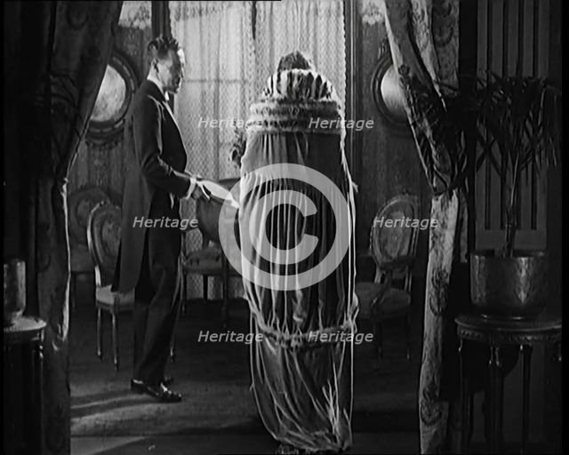 A Civilian Couple Wearing Evening Outfits Entering a Drawing Room, 1920. Creator: British Pathe Ltd.