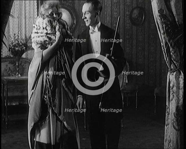 A Civilian Couple Wearing Evening Outfits Ready to Leave for an Event, the Male Holds a Top..., 1920 Creator: British Pathe Ltd.