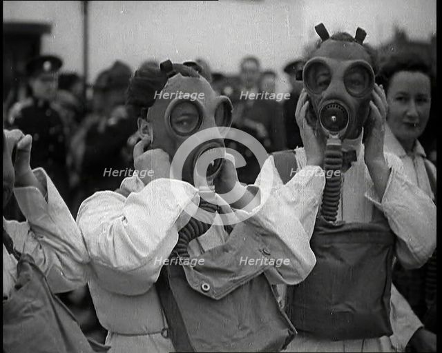 A Close up of Three Female Civil Defence Volunteers in White Boiler Suits Putting on Gas..., 1938. Creator: British Pathe Ltd.