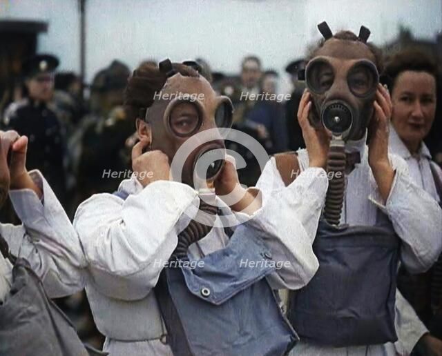 A Close up of Three Female Civil Defence Volunteers in White Boiler Suits Putting on Gas..., 1938. Creator: British Pathe Ltd.